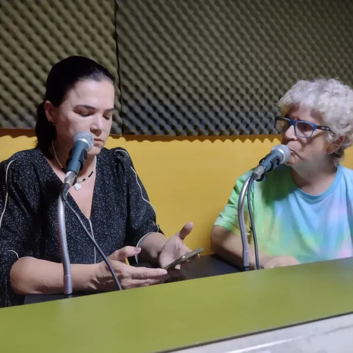 Duas pessoas falando ao microfone em um programa de rádio.